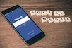 space gray iPhone 6 with Facebook log-in display near Social Media scrabble tiles
