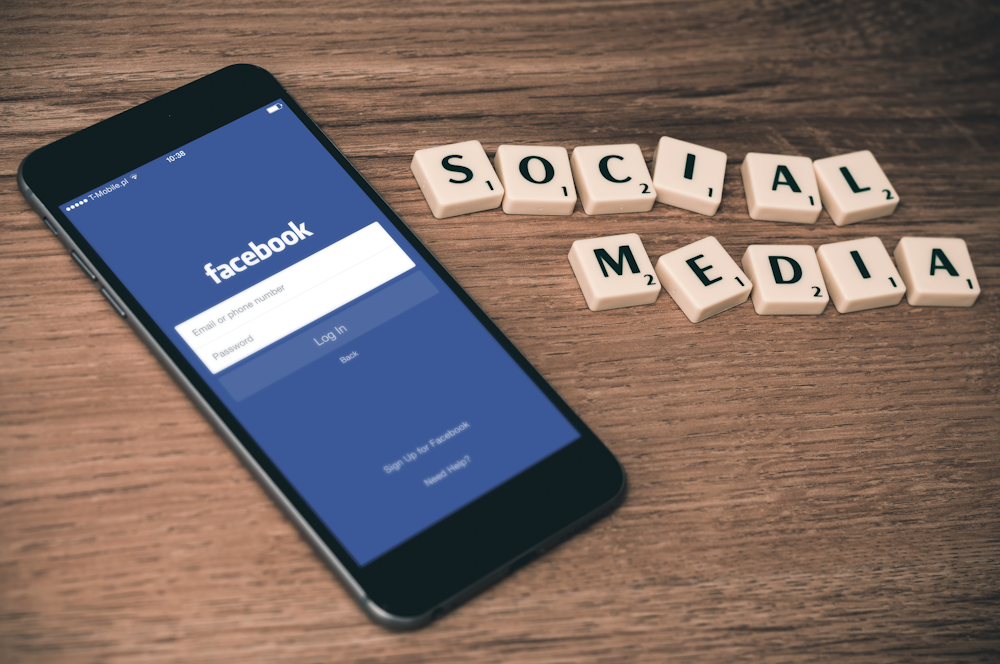 espaço cinza iPhone 6 com Facebook log-in display perto de redes sociais scrabble tiles