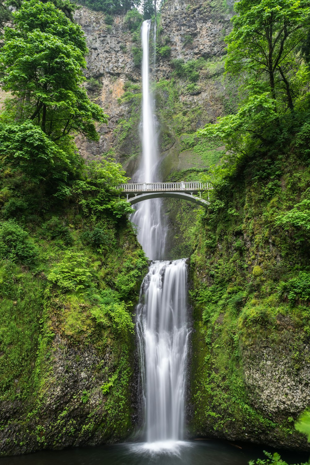 gray concrete bridge and waterfalls during daytime