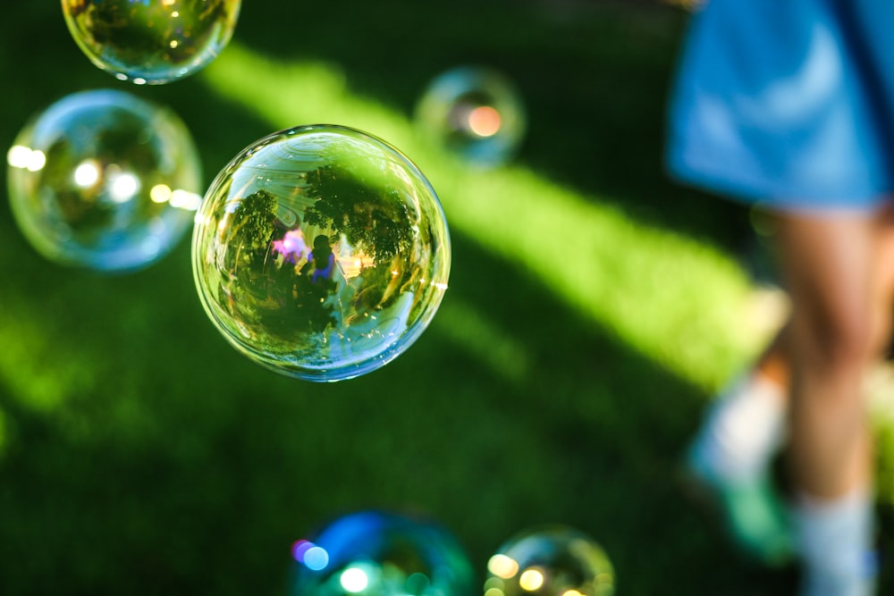 person wearing blue shirt on green grass with bubbles