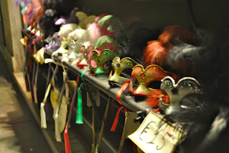 Colorful Mardi Gras masks and feathers scattered across a rustic wooden table.