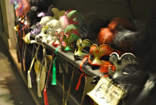 Colorful Mardi Gras masks and feathers scattered across a rustic wooden table.