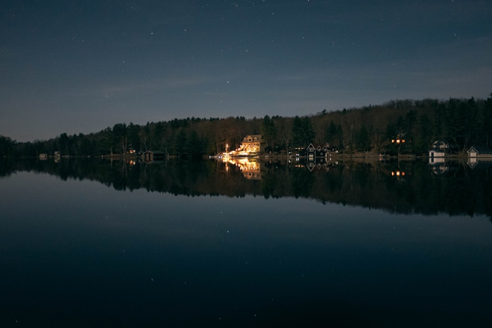 lighted beige house beside shoreline during nighttime