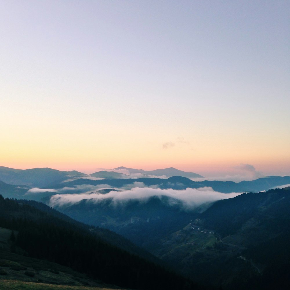 green mountains with fog during golden hour