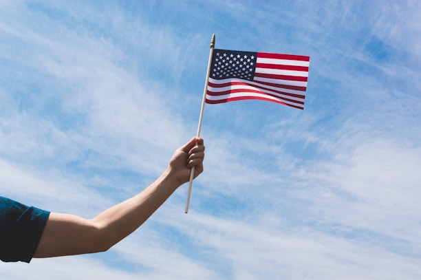 A close-up of hands holding a small US flag next to business documents.