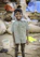 A smiling young entrepreneur standing proudly in front of his small shop, holding a tablet showing growth charts.
