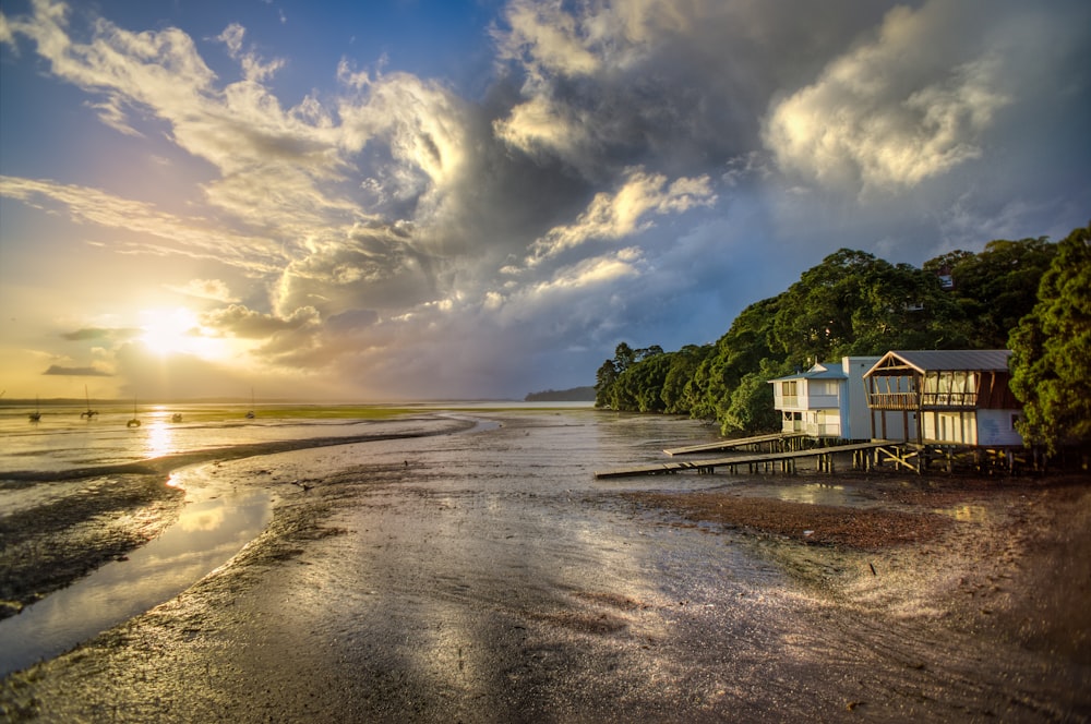 Photo d’une maison en bois blanc et brun au bord de la mer au lever du soleil