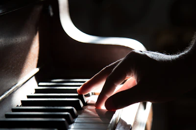A close-up of a young student’s hands gracefully playing a grand piano under warm stage lighting.