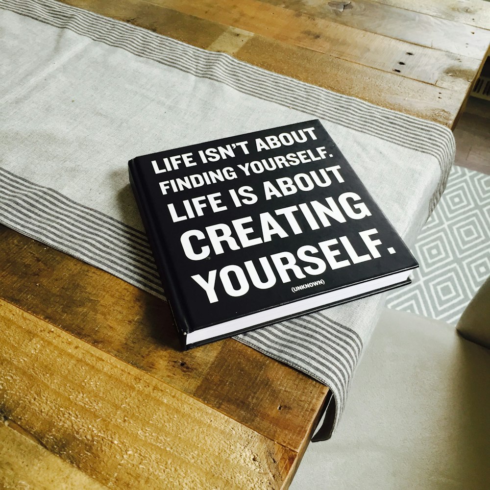 A black book with the title "Life isn't about finding yourself. Life is about creating yourself."