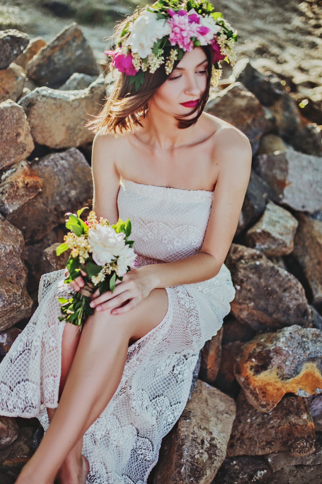 woman in white tube dress sitting on rock