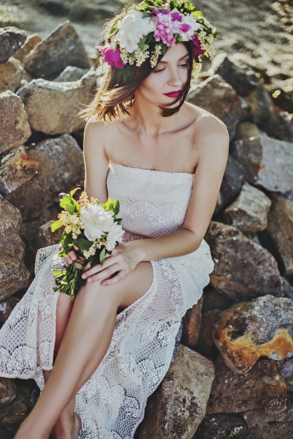 woman in white tube dress sitting on rock