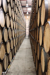 A sleek, modern warehouse with neatly stacked barrels of motor oil and lubricants under bright lighting.