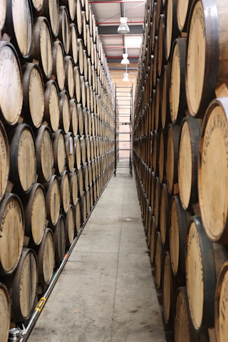 A sleek, modern warehouse with neatly stacked barrels of motor oil and lubricants under bright lighting.