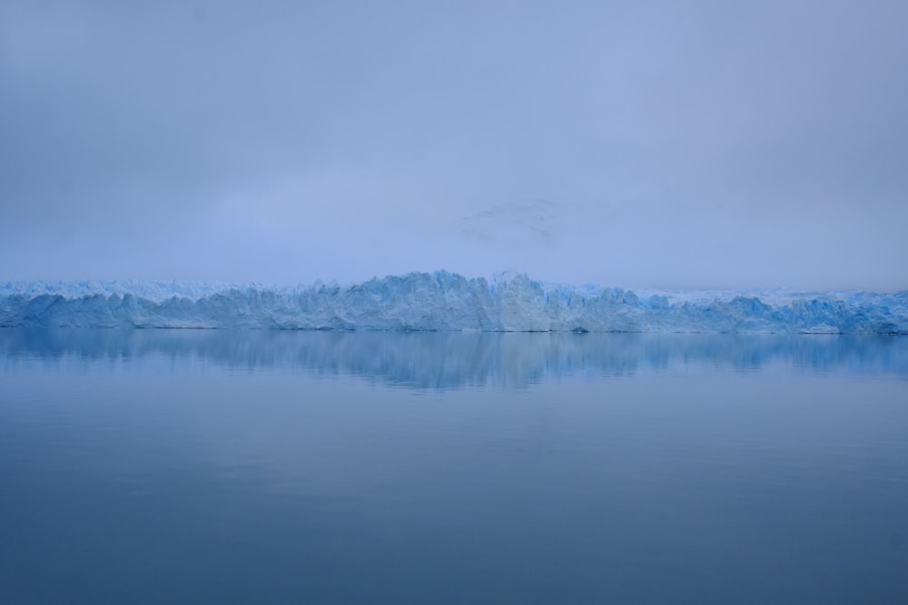 photography of sea near mountain covered with snow