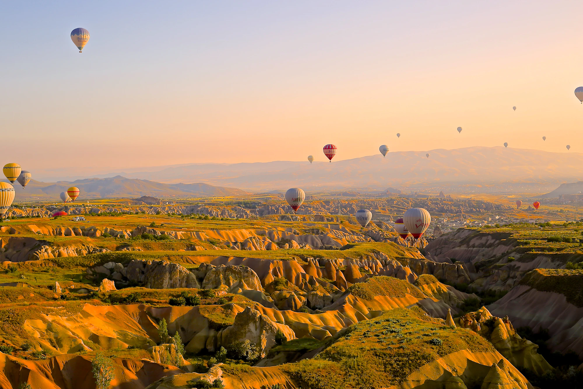 Hot air balloons soar at sunrise over the unique golden landscapes of Cappadocia, providing a breathtaking view.