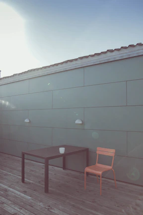 A clean, simple outdoor dining setup with light wood furniture and subtle navy accents.