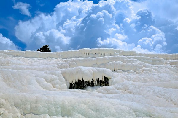 Mineral formations hanging from a travertine terrace under summer cloud — Pamukkale, Turkey