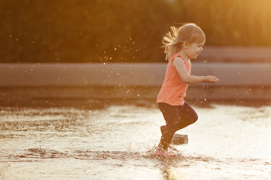 girl in pink tank top and brown shorts running on water during daytime