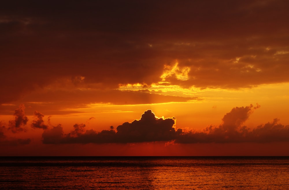 foto do oceano sob o céu nublado foto tirada durante o pôr do sol