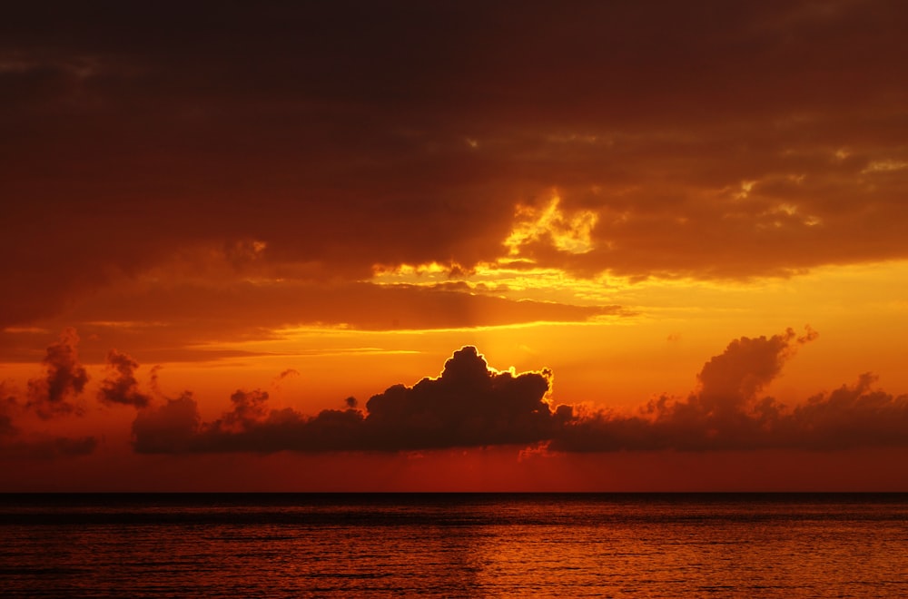 Foto des Ozeans unter bewölktem Himmel, aufgenommen während des Sonnenuntergangs