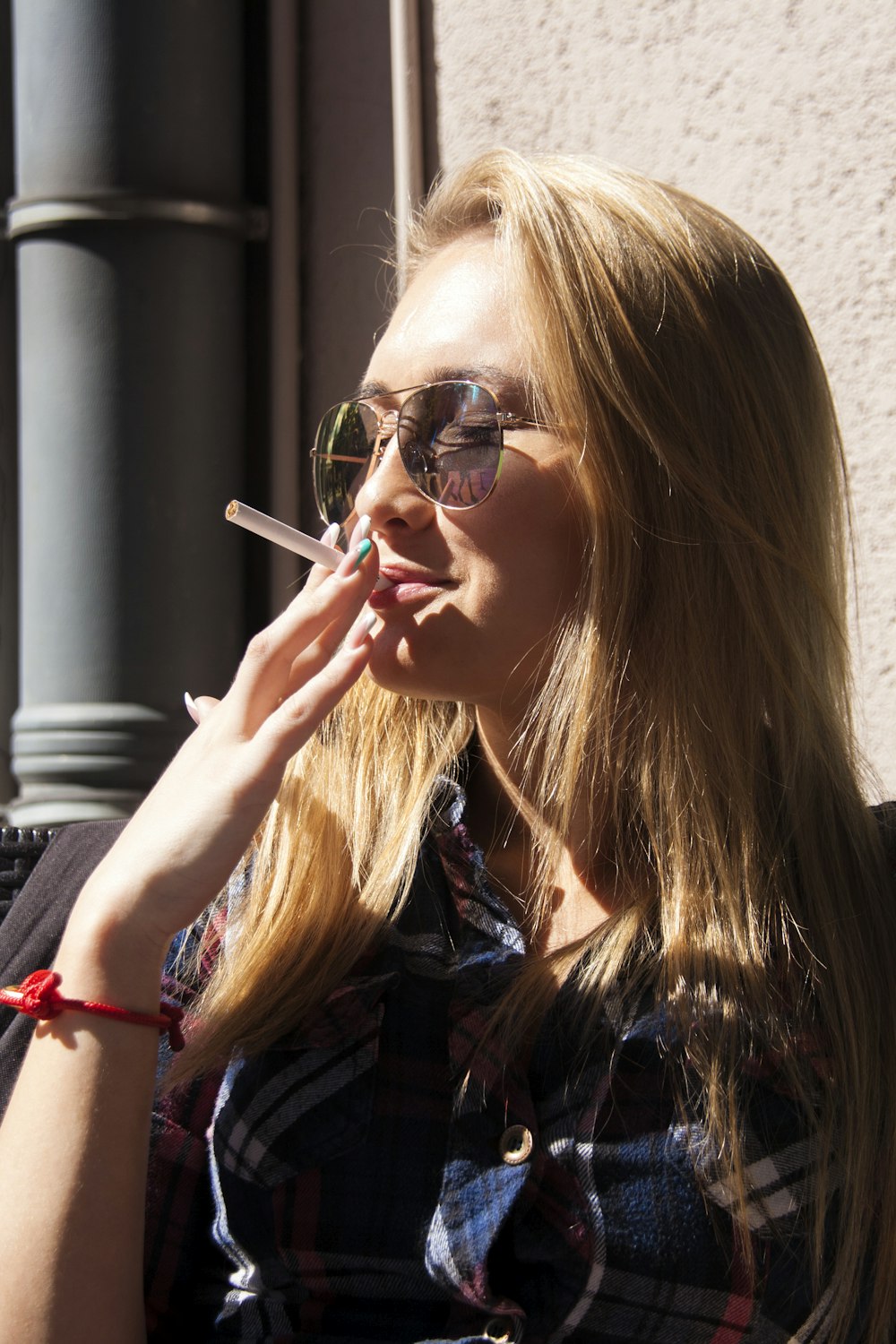 photographie en gros plan d’une femme tenant un bâton de cigarette pendant la journée