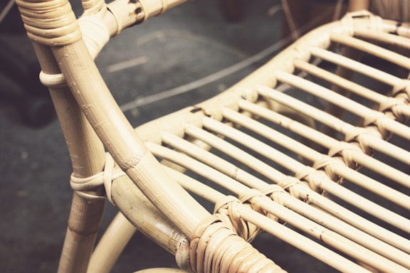 Close-up view of a woven rattan chair with intricate patterns. The chair features natural beige tones with visible texture and a focus on the craftsmanship of the weave.