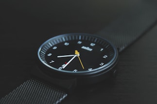 round black Braun analog watch with black band at 7:30