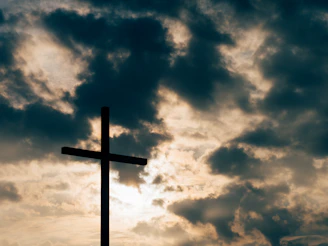 silhouette of cross under cloudy sky