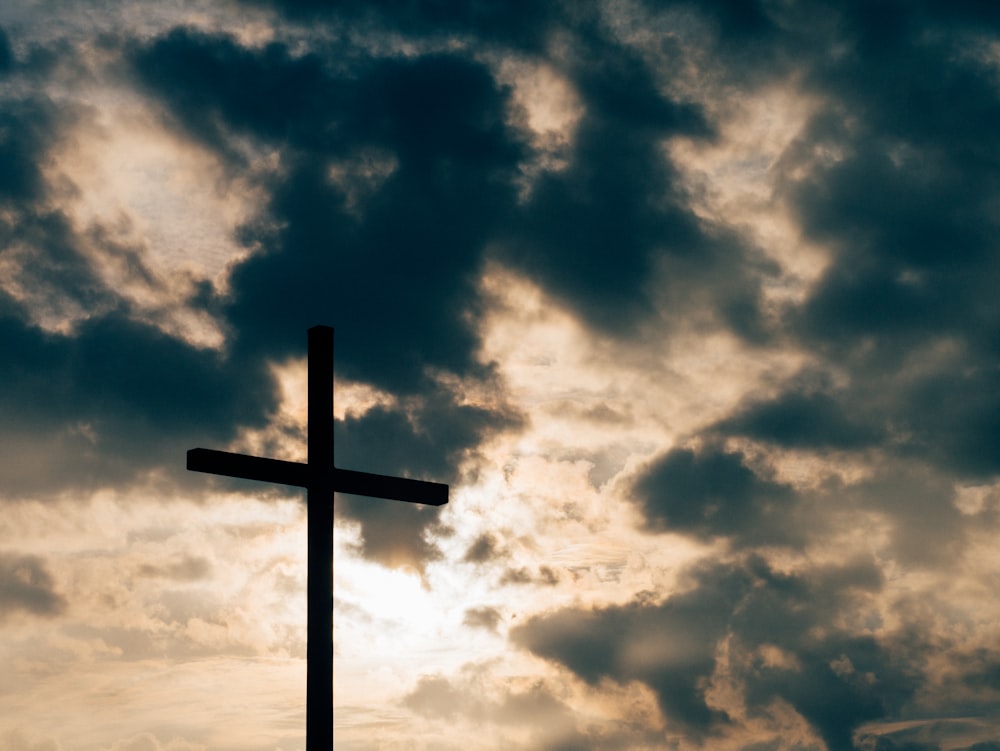 silhouette of cross under cloudy sky