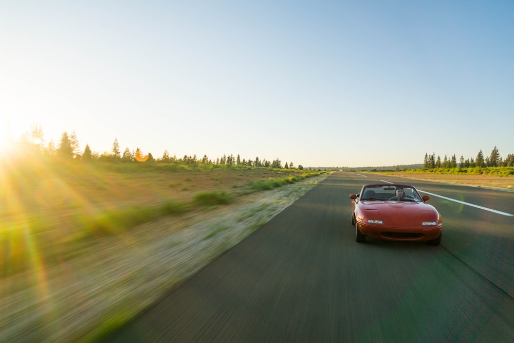 panning photography of red Mazda MX-5 Miata