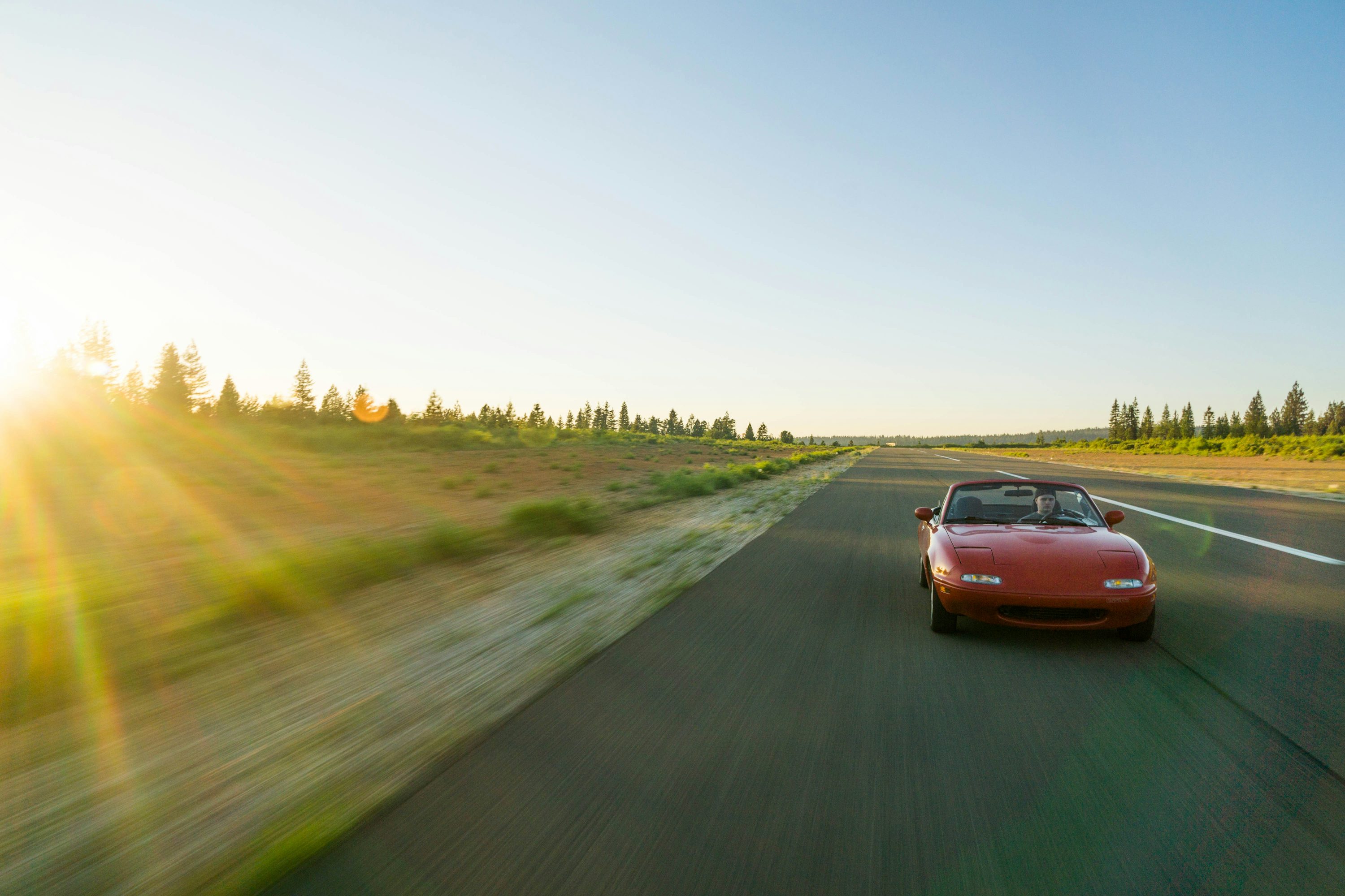 panning photography of red Mazda MX-5 Miata