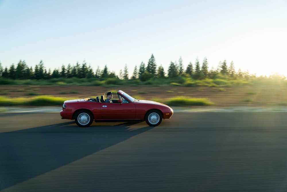 panning photography of man in red convertible
