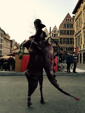 Tall stilt walker dressed in a whimsical costume entertaining a lively crowd.
