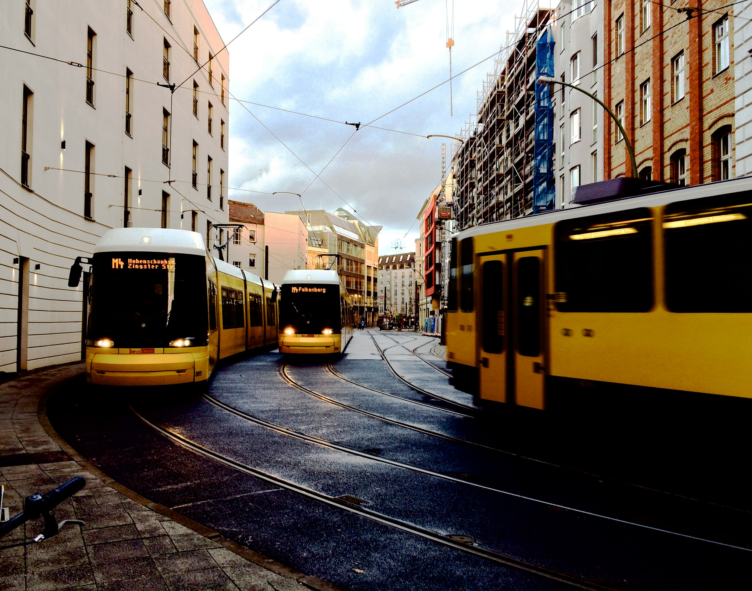 yellow city buses between buildings during daytime