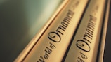 Close-up of a pair of book spines with a beige cover and elegant, decorative black text. The lettering is ornate and the focus is on the design style.