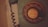 A vintage rotary dial telephone with a coiled cord is seen. The dial has numbers from 1 to 0 and a central circle with the text '378291 CTNE'. The phone is an old-fashioned device with a dark, muted color palette.