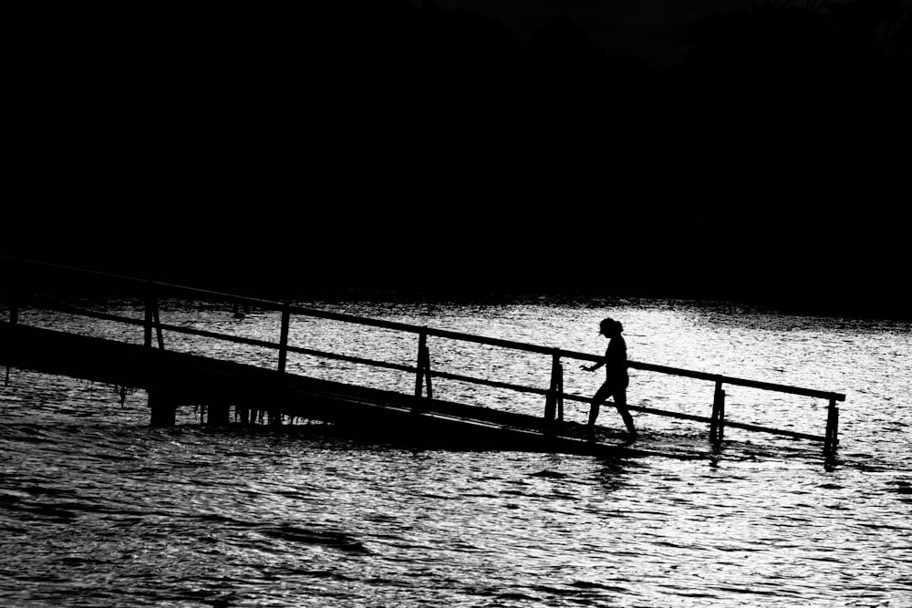 person walks on brown pier over body of water