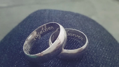 A pair of intertwined constellation rings symbolizing a couple’s bond, displayed on a marble surface.