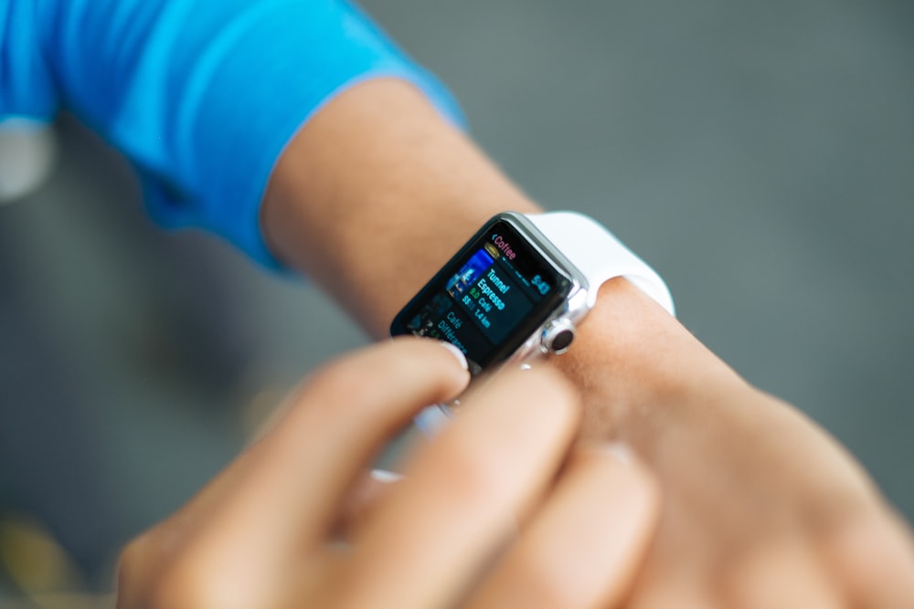 persona que usa Apple Watch plateado con correa deportiva blanca