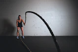 A dynamic scene of someone using a battle rope, muscles engaged and sweat visible.