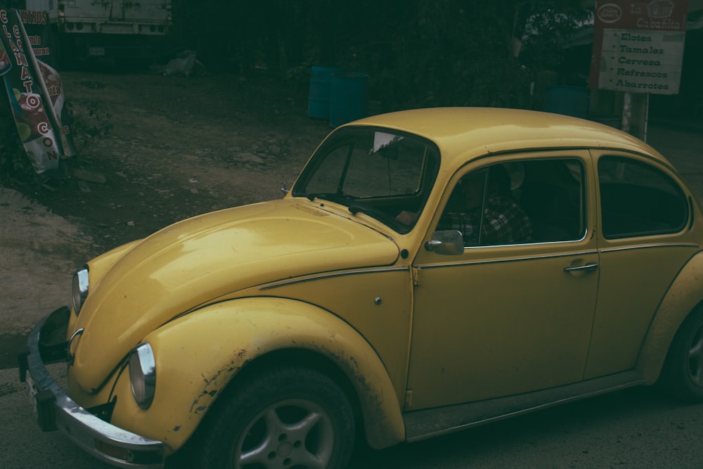 yellow Volkswagen Beetle coupe parked near white signage