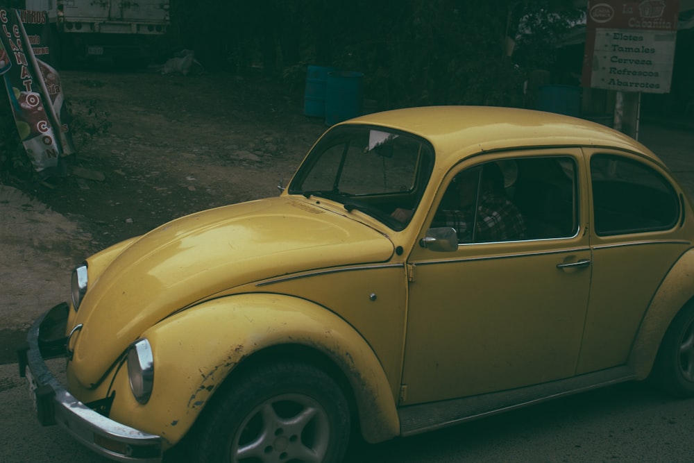 Volkswagen Beetle coupé amarillo estacionado cerca de letreros blancos