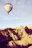 A happy woman enjoying a hot air balloon ride over scenic landscapes.