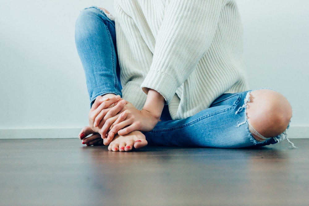 person wearing distressed blue denim jeans inside room