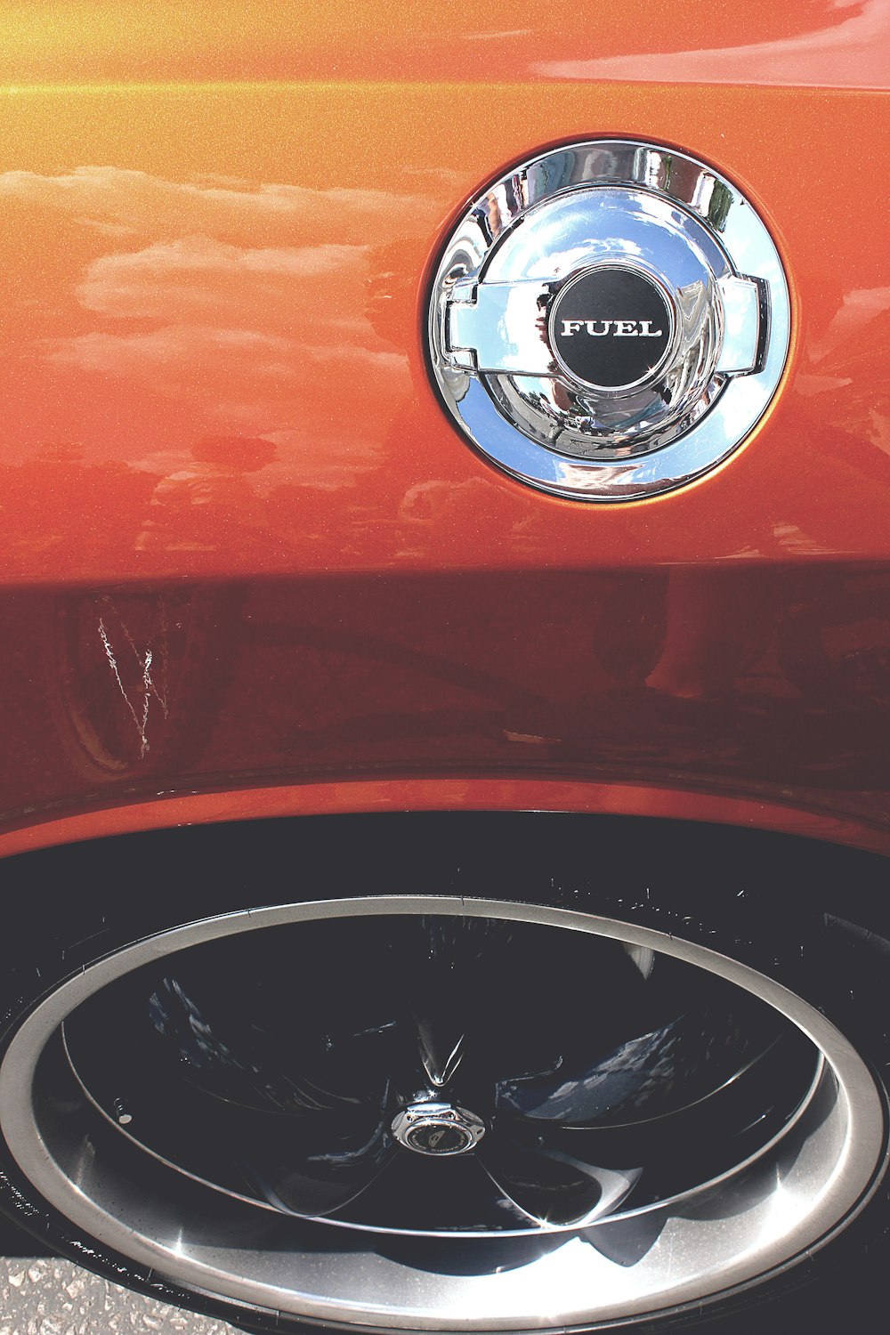 The fuel tank cap on an orange car.