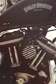 Detailed view of a Harley-Davidson motorcycle engine, showcasing the intricate metal components and branding with the Harley-Davidson logo prominently displayed on the gas tank.