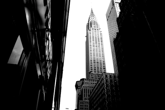 A striking black and white photo of a cityscape at dusk, highlighting contrasts and shadows.