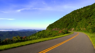 road near mountains under cloudy sky