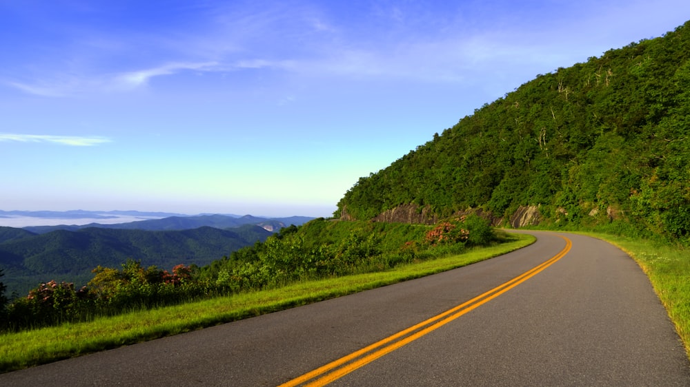 road near mountains under cloudy sky