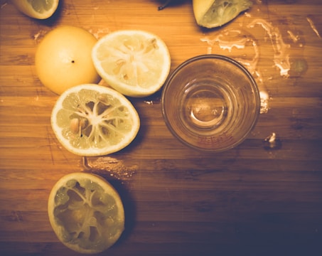 A fresh lemon sliced on a wooden cutting board with vitamin C tablets beside it.